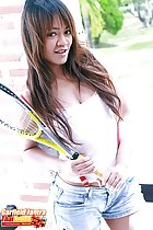 Holding tennis racquet long hair over her white top wearing denim shorts