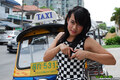 Standing in front of taxi wearing checkerboard outfit making heart symbol