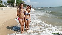 Girls standing in beach surf wearing bikinis